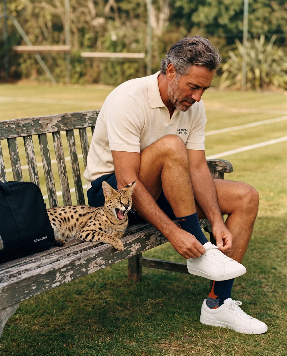 Player tying his shoe on a courtside bench while a serval yawns beside him