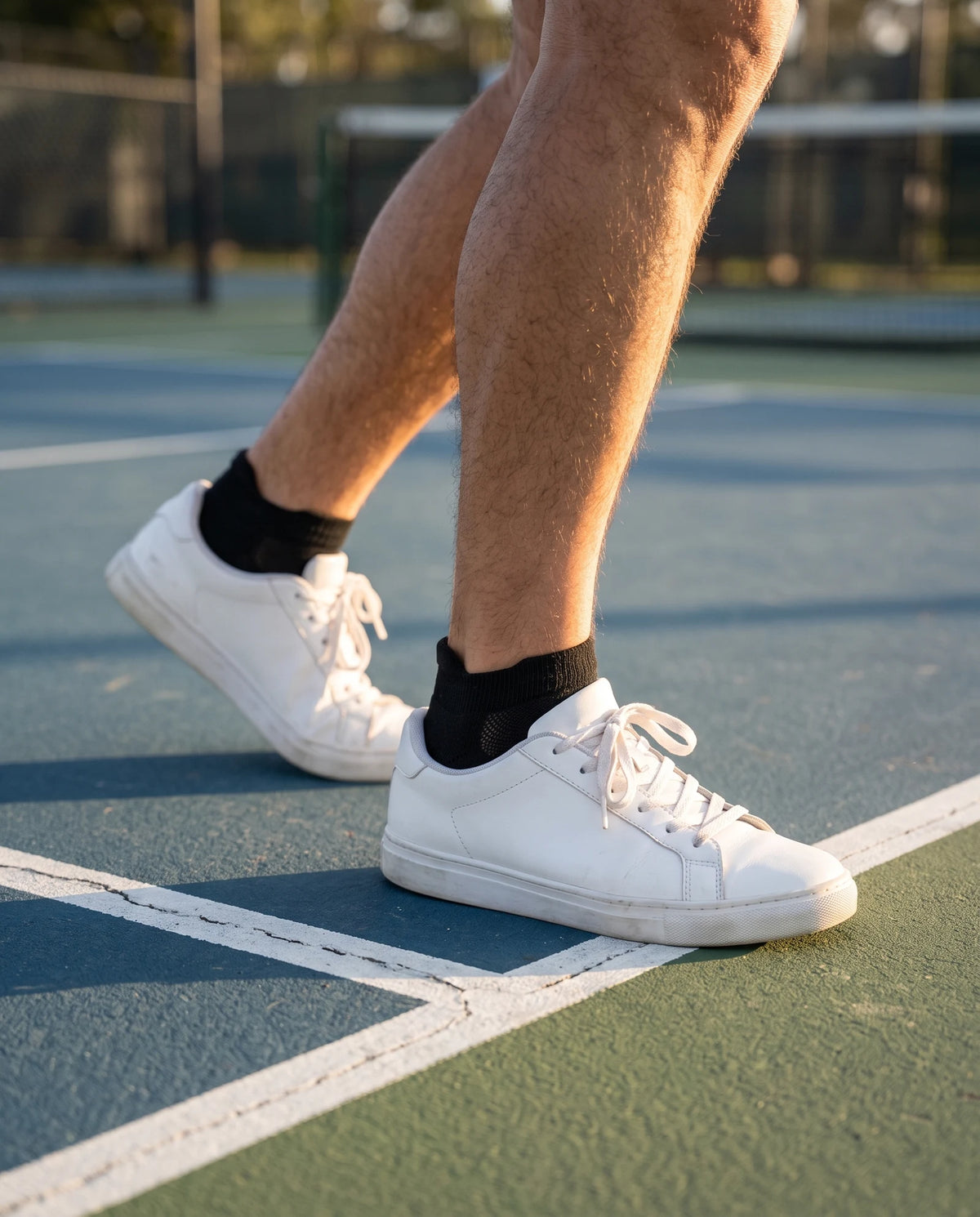 Black low-cut socks with white court shoes on a pickleball court