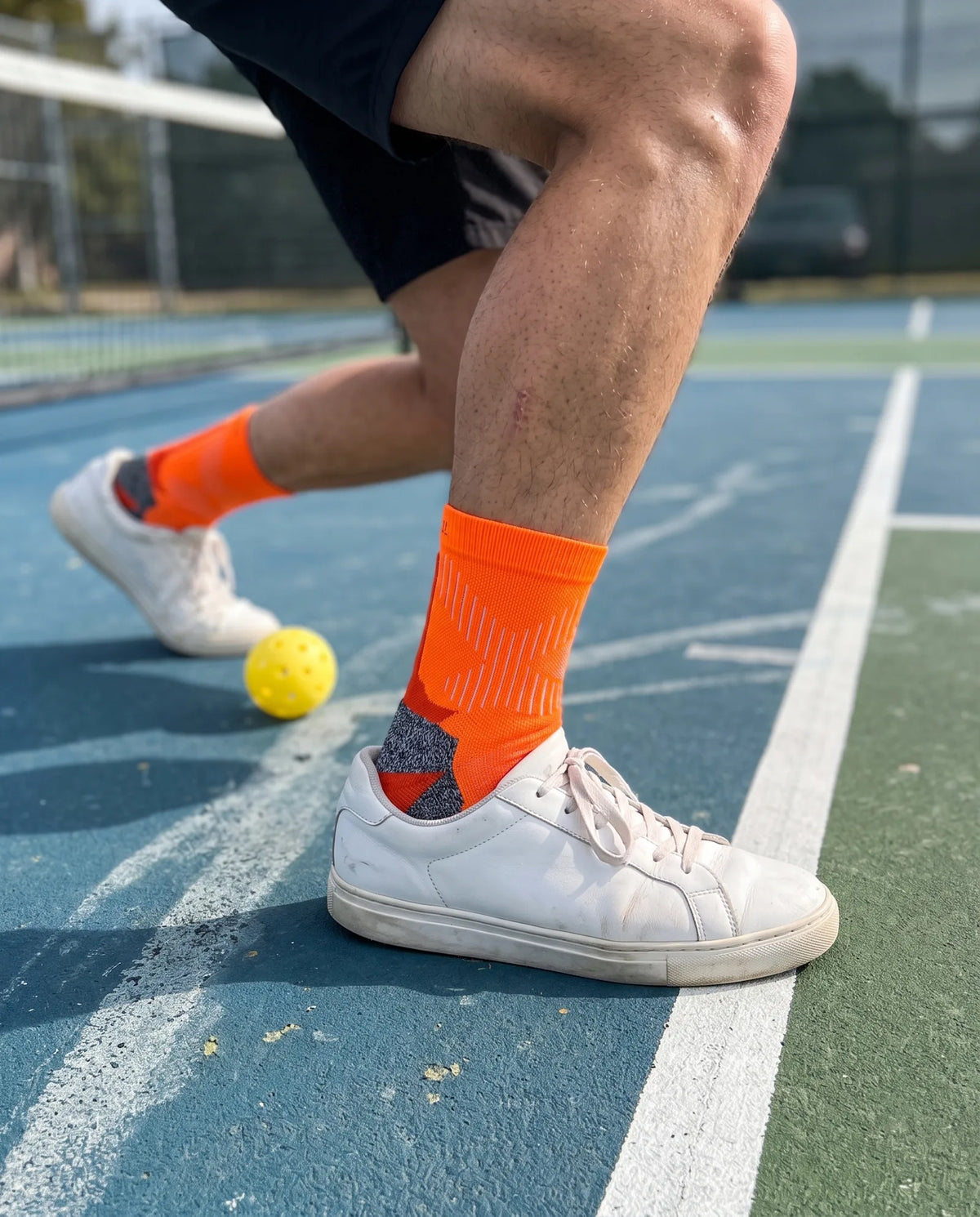 Court Crew in Rally orange, mid-lunge on a pickleball court