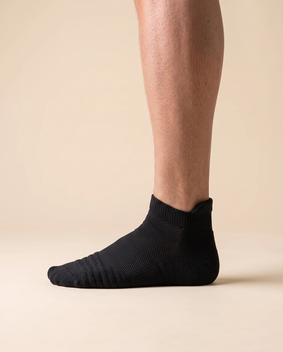 Black low-cut court sock with padded heel tab, worn on foot, side view