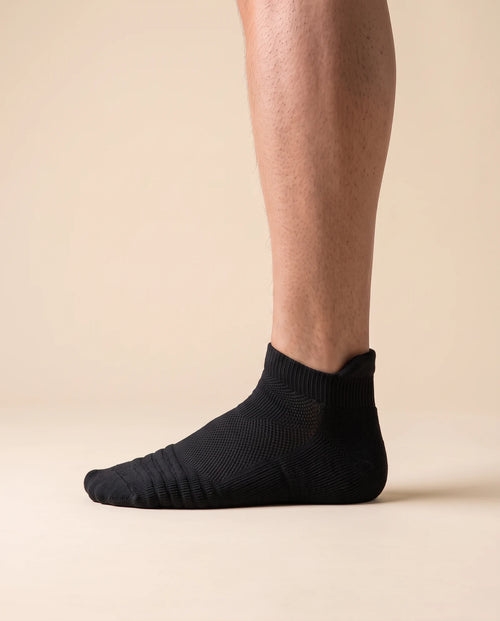 Black low-cut court sock with padded heel tab, worn on foot, side view